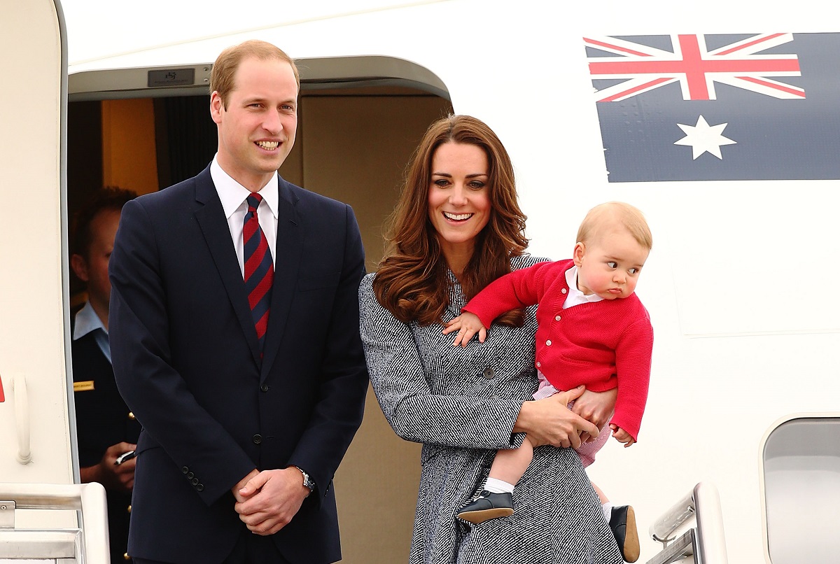 Kate Middleton, Prințul William și Prințul George coborară dintr-un avion. Kate e îmbrăcată într-o haină gri, Geroge e îmbrăcat în roșu, William e îmbrăcat în negru