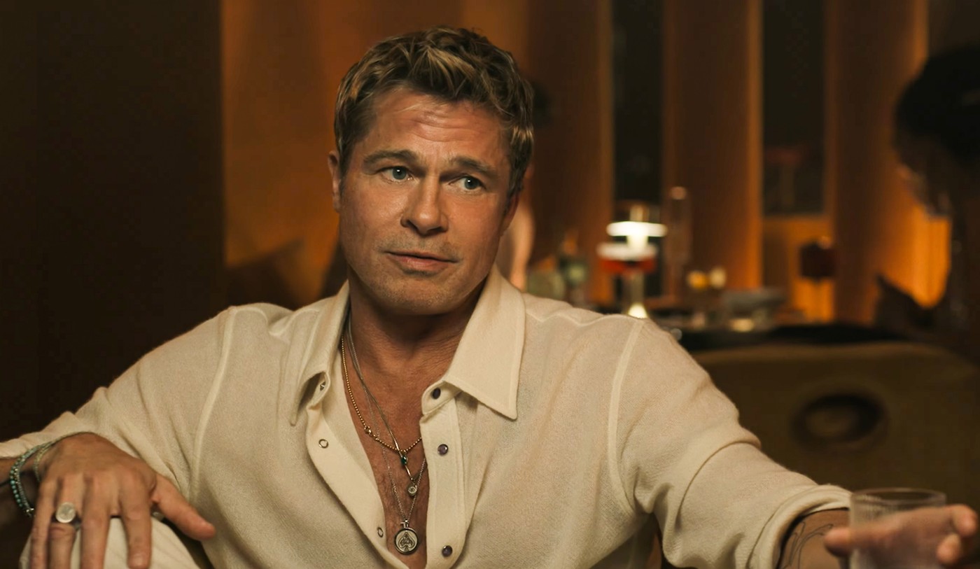 Brad Pitt, pe un scaun, într-o cămașă albă